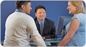 Photo of a bank officer discussing a transaction with two customers.